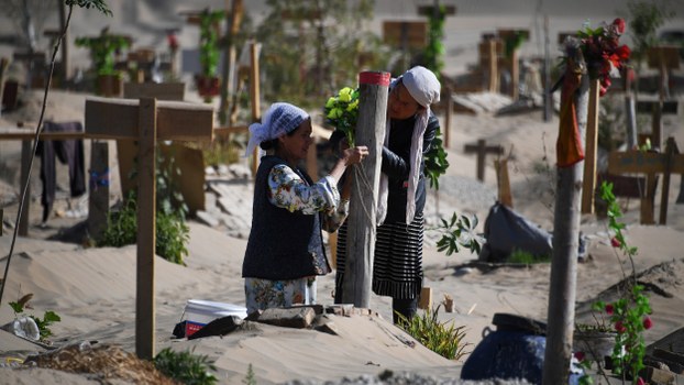 Two women decorate a grave in a Uyghur graveyard on the outskirts of Hotan in China's northwest Xinjiang region, May 31, 2019.